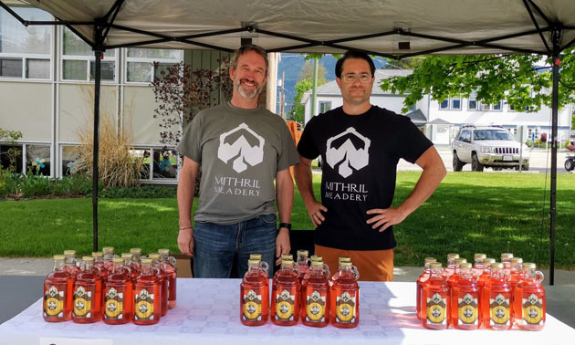 Owners of Mithril Meadery standing in front of display at farmers market table. 