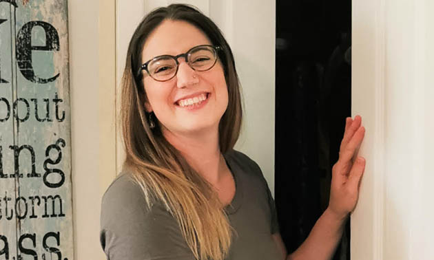 Veronica Roberge stands in front of a partially open closet, smiling into camera. 