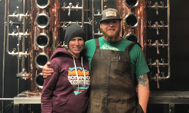 Jennifer and Josh McLafferty standing in front of distillery. 