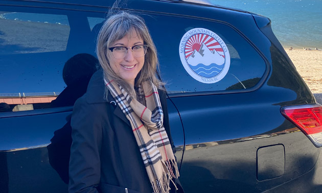 Cherie Evans, standing beside black van that has Morning Mountain Coffee Co. logo on it. 