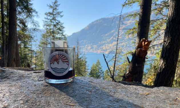 View of glass coffee mug with lakeview in distance. 