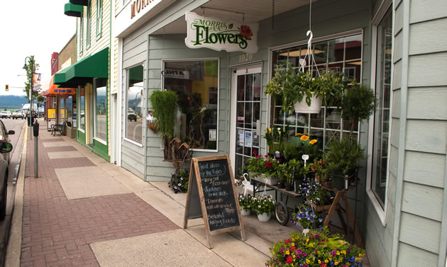 A light blue shop has plants and attractive wares around the entrance.
