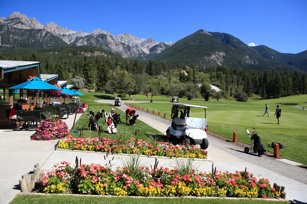 Flower beds and golf course in the foreground, mountains and blue sky behind