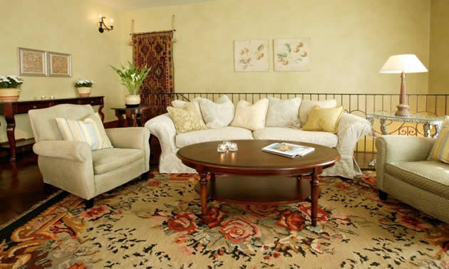 A rug in muted shades of cream, red and black dominates a sitting area with a cream-coloured sofa and chair 