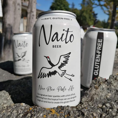 Three cans of Naito beer, outside photo, blue sky in background. 