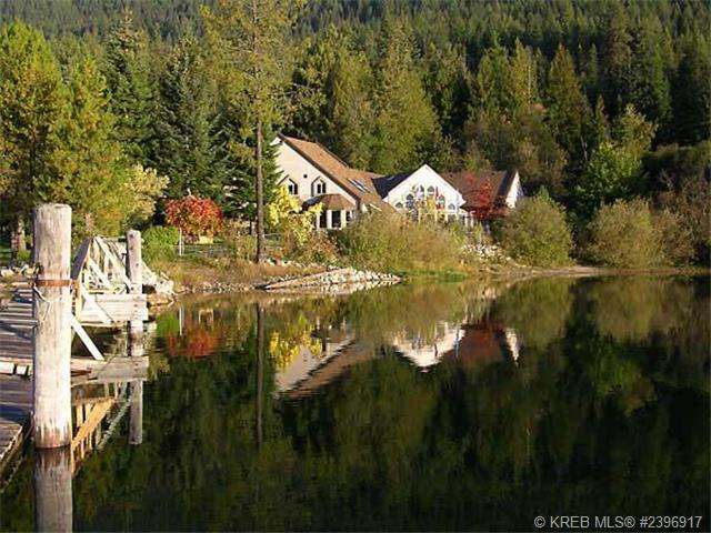 Home near Nelson reflecting in the water of Kootenay Lake.