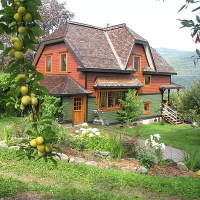 Picture of eco-house in middle of orchard, with view of lake in background. 