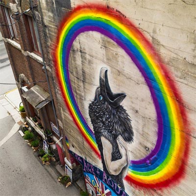 Mural of wolf inside rainbow on building. 