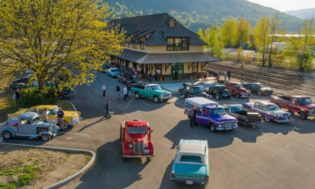 Nelson & District Chamber of Commerce building, with classic and vintage cars in parking lot. 