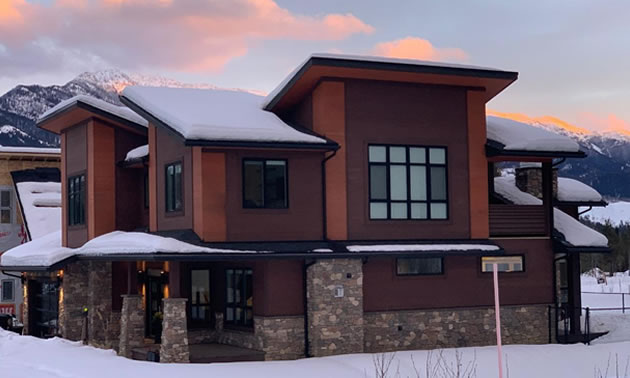 Modern-style home with large windows and stone facing. 