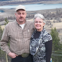 Middle-aged couple in casual clothing stand on high ground overlooking wetlands and forest