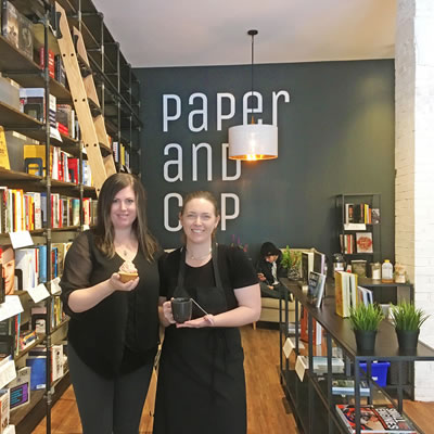 Brandi O'Neill (L), owner, and one of her staff stand next to a tall shelf of books.