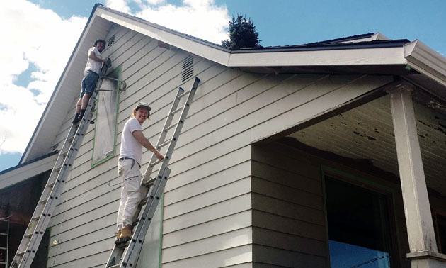 Joel Godbee on ladder painting side of house. 