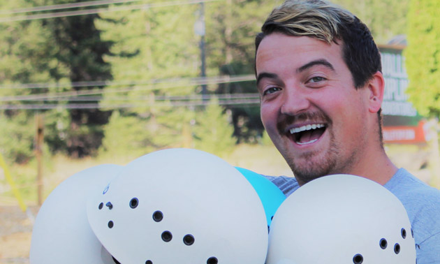 Patrick Tolchard holding a bunch of helmets. 