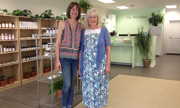 The two owners, Petra and Tiffany Ware, are standing in their store with body care products on shelves behind them.