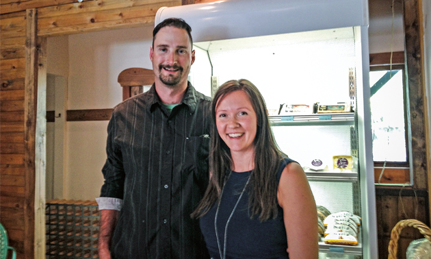 The two owners, Matthew Harris and Ella Markan, stand in front of a cheese case.