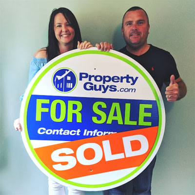 Andy and Sinead Britner stand behind Property Guys SOLD sign. 
