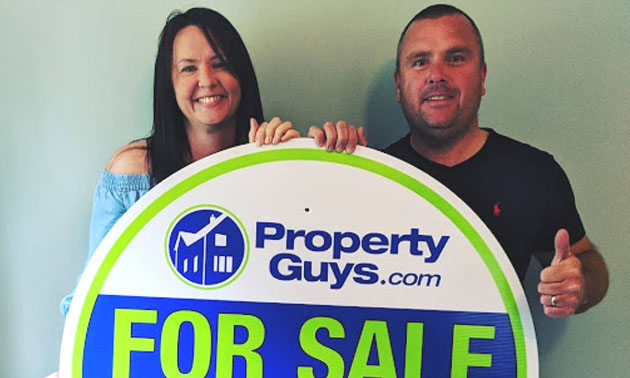 Andy and Sinead Britner stand behind Property Guys SOLD sign. 
