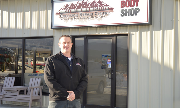 Man in dark casual clothing standing in front of a storefront under a sign saying Rocky Mountain Diesel Body Shop