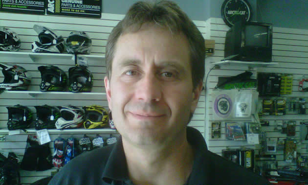 Close-up of smiling man with a merchandise display wall in the background