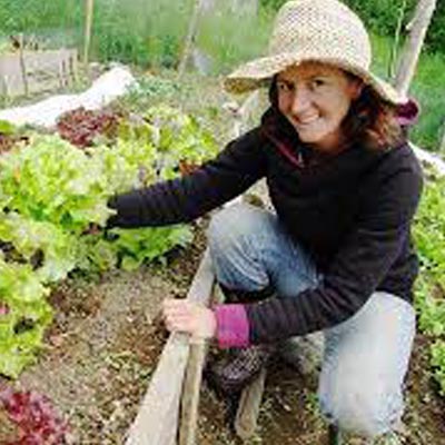 Rachael Roussin sitting beside lettuce patch. 