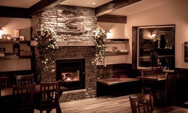 Interior of Radium Brewing showing wood-topped tables, stone fireplace. 