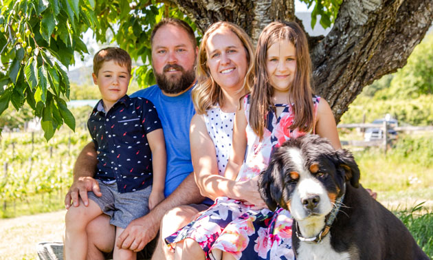 The Cardinal family sitting under a tree with their dog. 