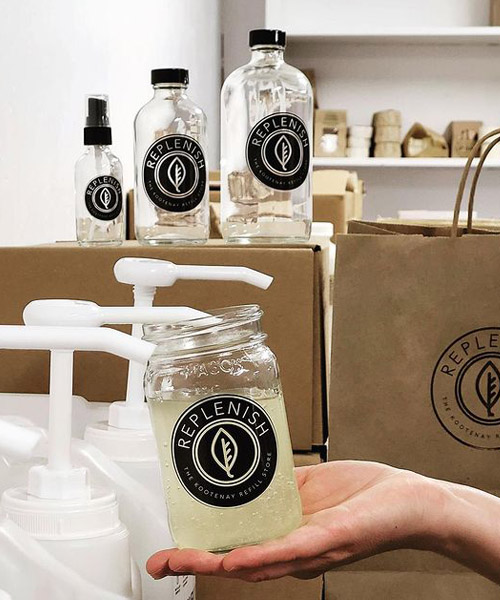 Row of large glass pump-top jars and smaller jars sitting on top of boxes. 