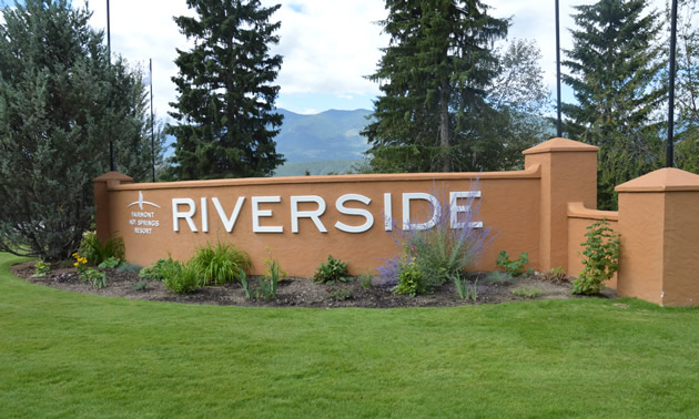 Low curved red-brick wall bearing the name 'Riverside' in white lettering