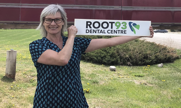 Heather Lang holds a small sign for Root 93 Dental Centre