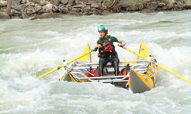 a man on a pontoon raft on in the middle of rough rapids