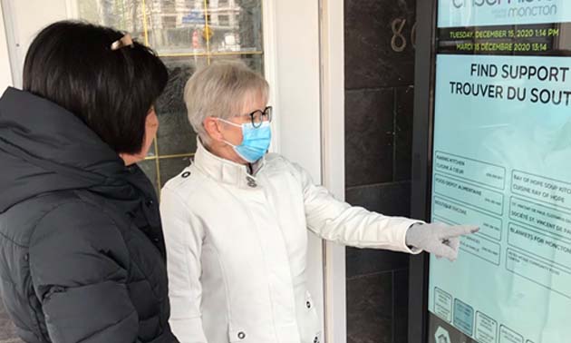 Two people touching a screen on a smart vending machine. 