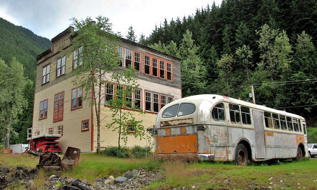Dilapidated old buses in front of old building. 