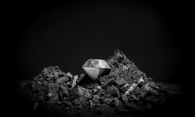 Black-and-white photo of a silvery-coloured diamond on a pile of fine, dark rock rubble 