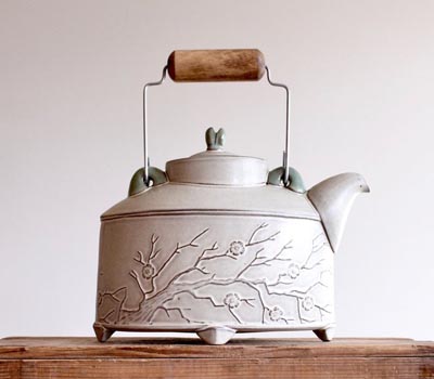 White hand-made teapot decorated with branches. 