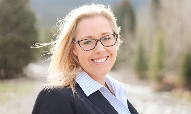 Head shot of smiling young blonde woman wearing glasses and business attire