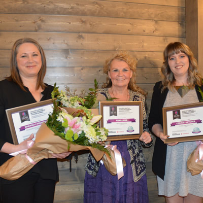 Three smiling  business-women holding bouquets of flowers: Shawna L'Heureux, Zen Mountain Float & Wellness, Kimberley; Anna Lamb, Pro-Fitness Gym,
