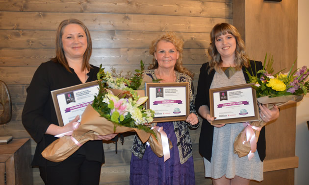 Three smiling  business-women holding bouquets of flowers: Shawna L'Heureux, Zen Mountain Float & Wellness, Kimberley; Anna Lamb, Pro-Fitness Gym,