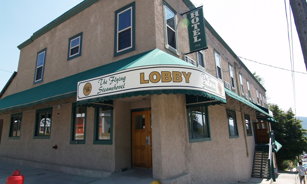 Two-storey, flat-roofed, grey building bears a sign reading Flying Steamshovel Hotel Pub