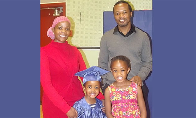 man and woman standing with two young children