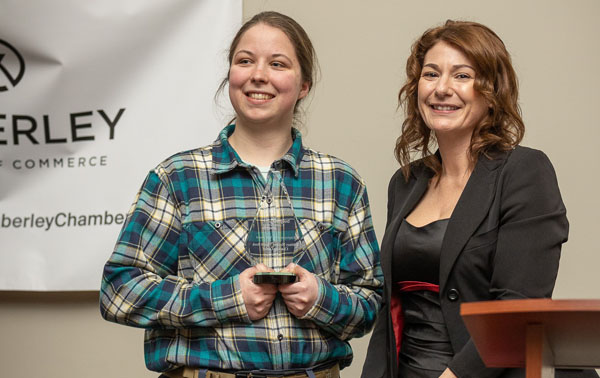 Brittney McLean holding Business Excellence award and smiling. 