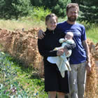 Young couple with infant stand in a vegetable field.