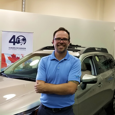 Subaru of Cranbrook's General Manager Jordan McKee stands in front of a new Subaru.