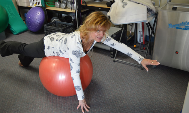 Blonde woman demonstrates use of a stability ball