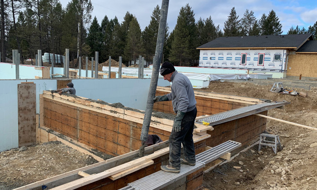 Kris Newman pouring foundation at a building site. 