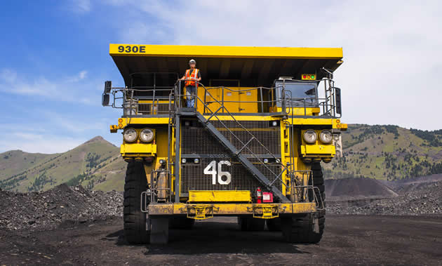 Sue Foraie, haul truck driver, at Fording River Operations, stands on the deck of a yellow haul truck.