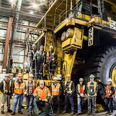 Picture of group of Teck employees standing in front of large machine. 