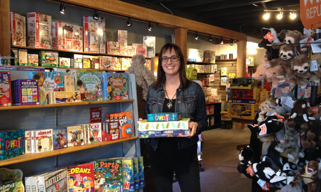 Zoe Ferguson, co-owner of Treehouse Toy Co., holds a stack of games in her newly opened store in Kimberley's Platzl.