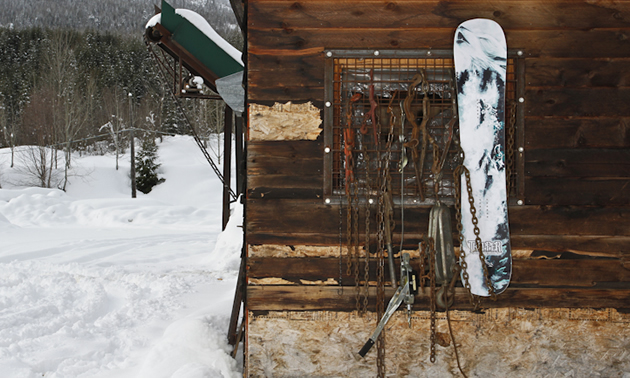 A white Howler snowboard is juxtaposed against an old wood wall.