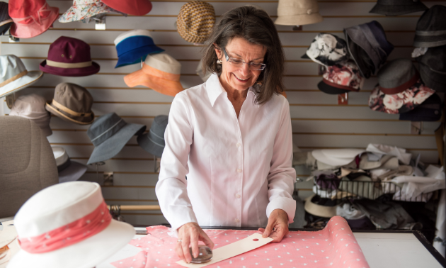 An array of colourful hats surrounding Liz Cohoe demonstrates the variety of headgear that is available from Nelson, B.C.-based company Lillie & Cohoe